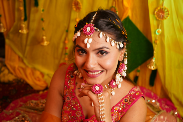 Bride smiling during colourful mehndi ceremony with floral jewellery
