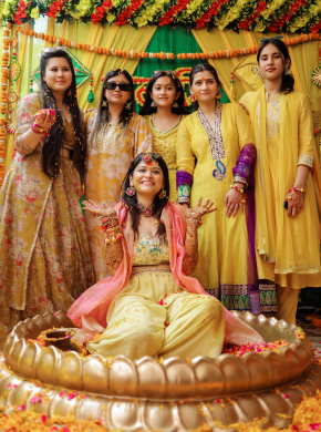 Bridesmaids posing together in coordinated yellow outfits at mehndi event
