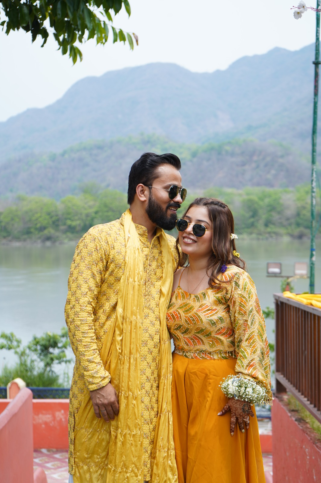 a man and woman standing on a deck by water - wedding photography