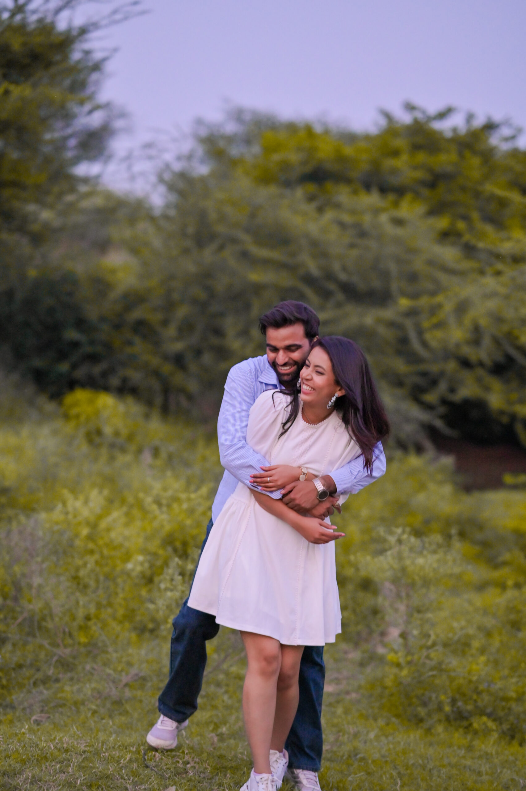 Couple holding each other in scenic open field during outdoor couple shoot