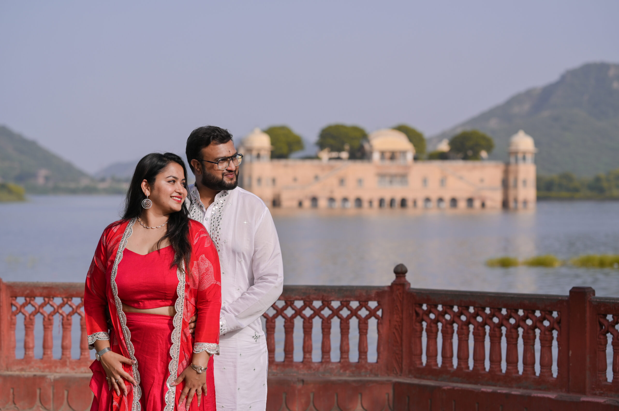 Bride and groom posing in ethnic wear near lakeside during photoshoot